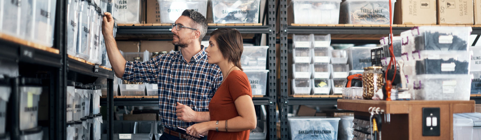 two workers looking at storage bins in a warehouse 