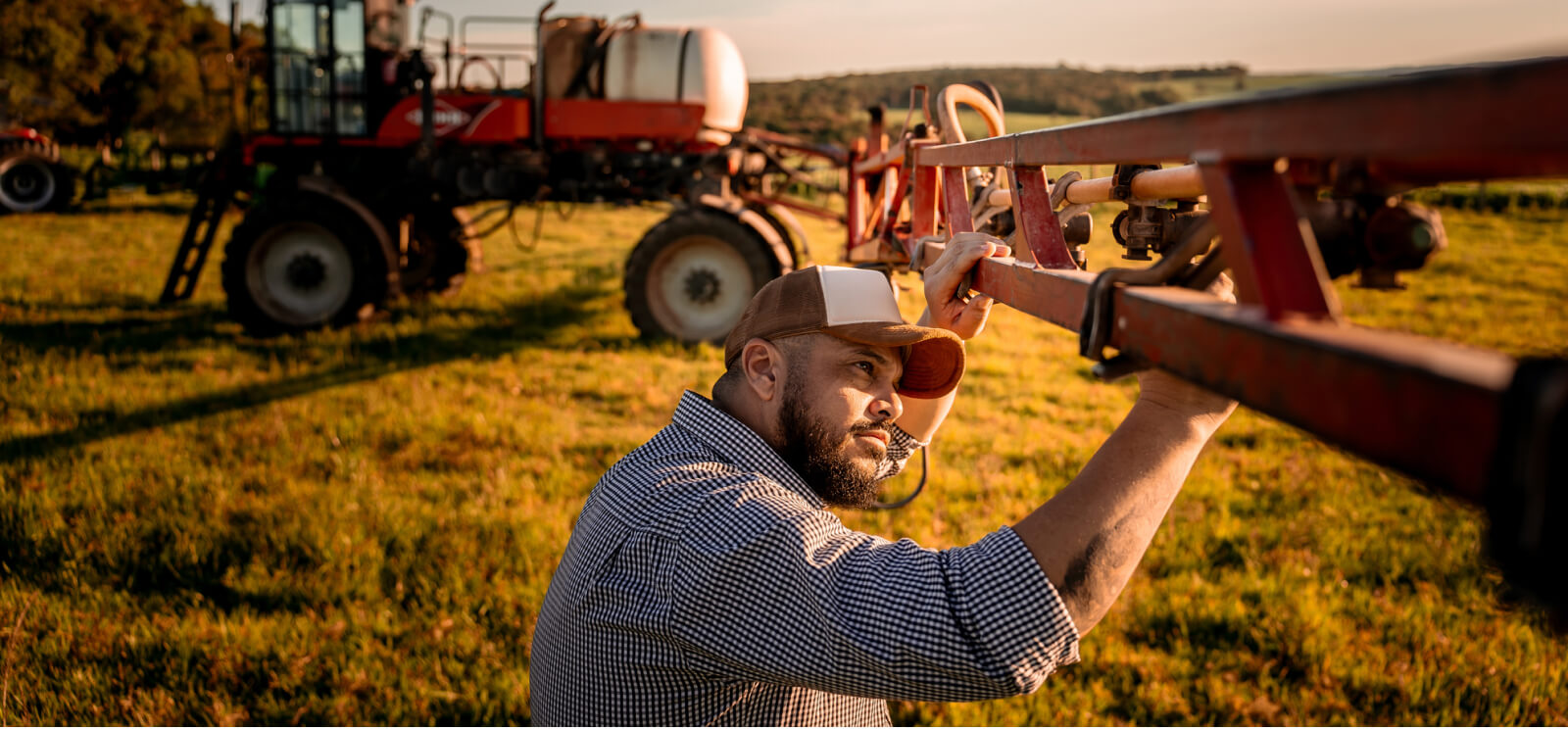 a farmer inspecting farm equipment in a field